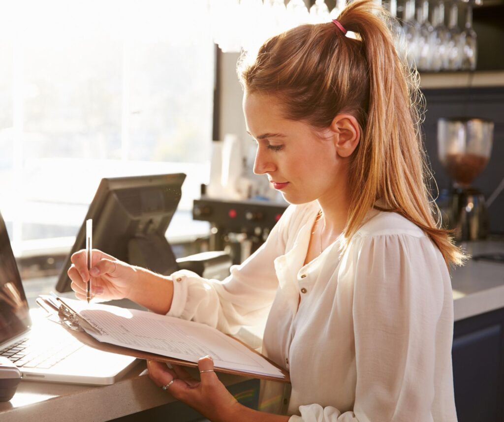 Restaurant manager reviewing menu notes and sales data to identify low-performing menu items for removal.